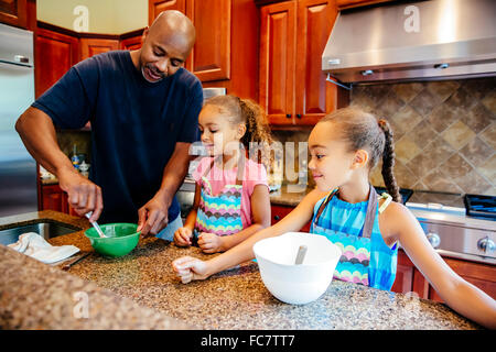 Father and daughters cooking in kitchen Stock Photo
