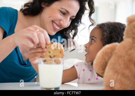 Mother and daughter eating milk and cookies Stock Photo