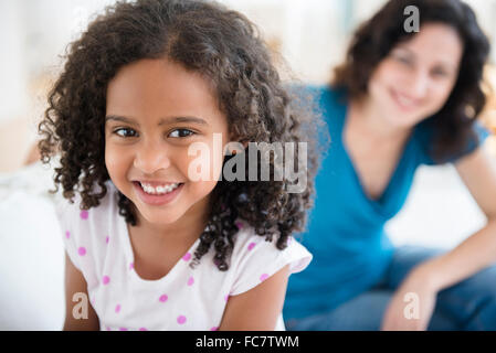 Smiling girl and mother on sofa Stock Photo