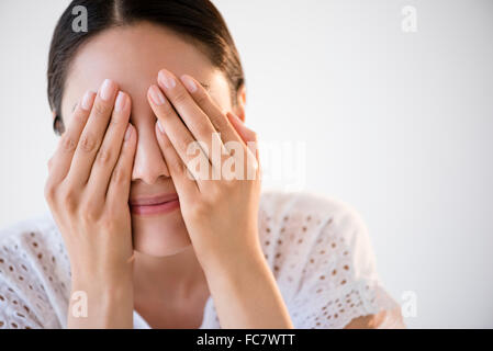 Hispanic woman covering her eyes Stock Photo