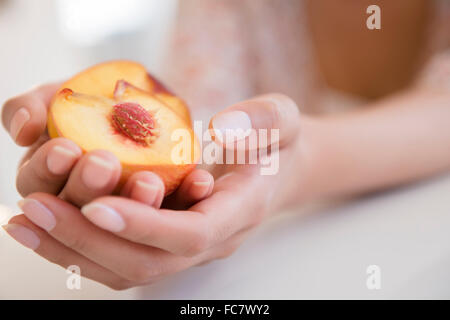 Hispanic woman holding halved peach Stock Photo