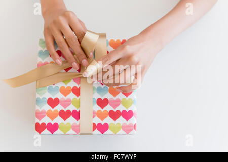 Hispanic woman tying ribbon on gift Stock Photo