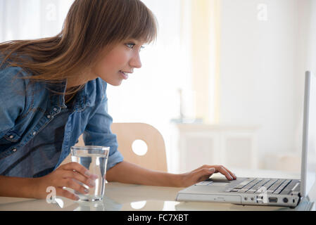 Mixed race woman using laptop on table Stock Photo