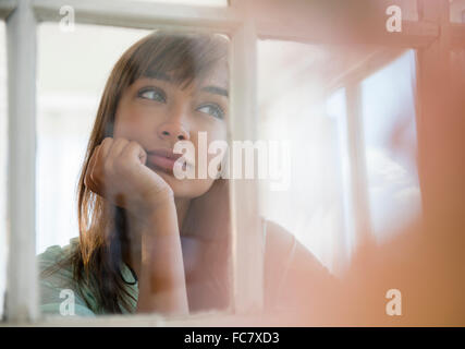 Mixed race woman looking out window Stock Photo