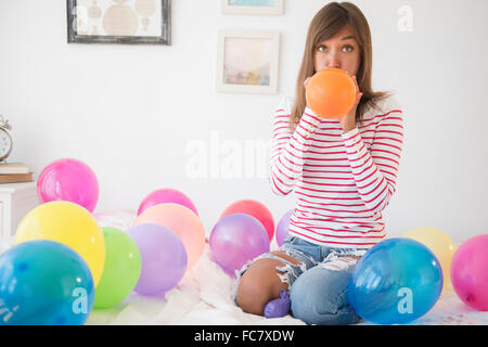 Mixed race woman blowing up balloons Stock Photo