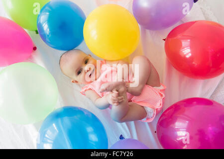 Caucasian baby girl laying in balloons