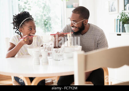 Black father and daughter eating noodles Stock Photo