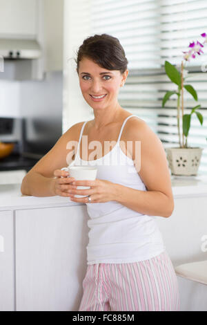 Caucasian woman drinking coffee in kitchen Stock Photo