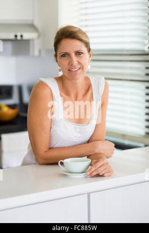 Caucasian woman drinking coffee in kitchen Stock Photo