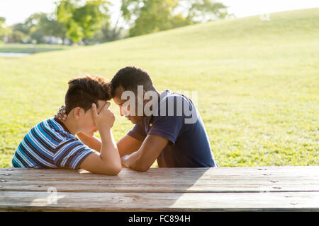 Father and son talking at table in park Stock Photo