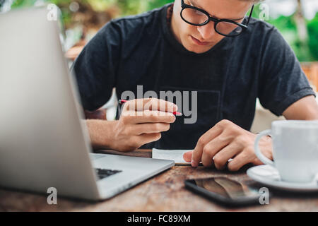 Caucasian man writing in cafe Stock Photo