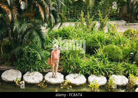 Caucasian woman standing on stone in pond Stock Photo
