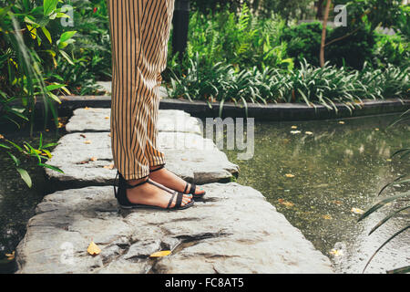 Caucasian woman standing on stone in pond Stock Photo