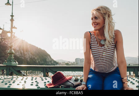Caucasian woman sitting on bridge Stock Photo