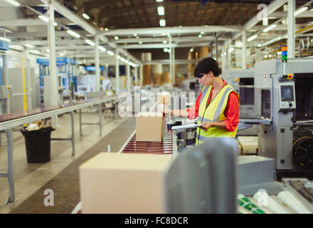 Worker checking cardboard boxes on conveyor belt production line in factory Stock Photo