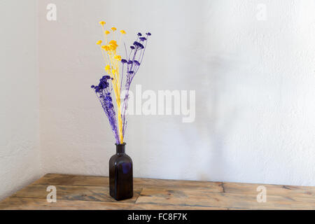 Dried flowers in blue bottle vase on wood Stock Photo