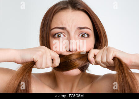 Closeup portrait of scared frightened young woman covered her mouth with her long hair over white background Stock Photo