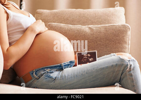 Pregnant woman at home holding ultrasound scan Stock Photo