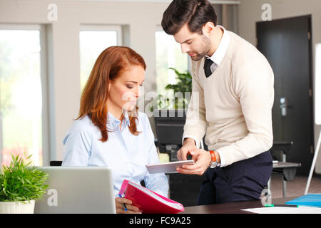 Young businessman holding digital tablet and presenting his idea to chief financial officer. Stock Photo