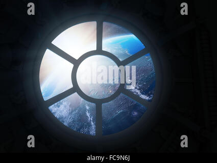 A round window on a space station with a view of Earth below Stock Photo
