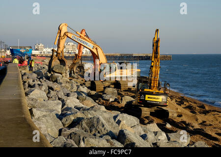 heavy plant machinery placing boulders to repair storm damaged promenade at southsea england uk Stock Photo