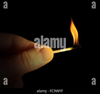 Hand holding burning match stick Stock Photo