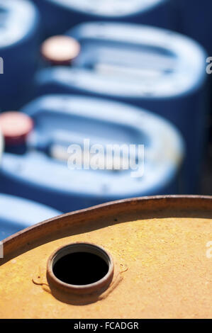 Old colored oil barrels and blue canisters Stock Photo