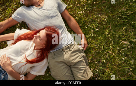Young woman lying on the lawn with her boyfriend. Overhead view of young couple relaxing on the grass, with copy space. Stock Photo