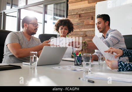 Portrait of young office workers meeting in a boardroom. Team of multiracial people discussing work in meeting room. Man giving Stock Photo