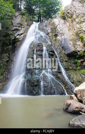 Waterfall comes out of a huge rock, Bucias Waterfall in Eastern Romanian Carpathians. Stock Photo