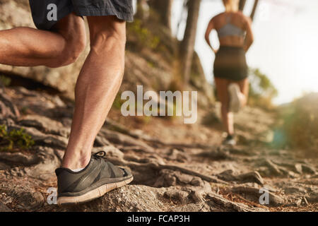Closeup of male feet run through rocky terrain. Cross country running with focus on runner's legs. Stock Photo