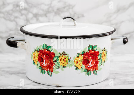 Empty white vintage enamel saucepan with flower design on white marble background Stock Photo