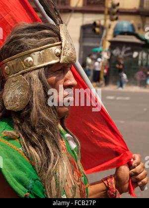 Peruvian Indian, disguised as Inca, flames Peruvian flag during a protest for the rights of indigenous peoples Stock Photo