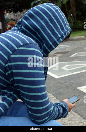 Young man looking at mobile phone in park in Tenerife, Spain Stock Photo