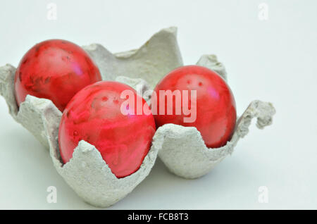 three red Easter eggs in a cardboard box, close up, isolated on  white background, horizontal Stock Photo
