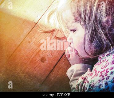 Close-Up Of Cute Young Girl Sleeping On Wooden Surface