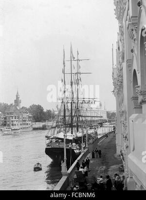 AJAXNETPHOTO. 1900. PARIS, FRANCE. - UNIVERSAL EXPOSITION - WORLD FAIR - THE THREE MASTED SQUARE RIGGED COD FISHING SHIP DEUX EMPEREURS MOORED NEXT TO THE PALACE OF ARMIES ON THE SEINE. IN THE BACKGROUND IS A MODEL OF OLD PARIS BY ARTIST AUBERT ROBIDA.    PHOTO; AJAX VINTAGE PICTURE LIBRARY REF:PAR EXPO 1900 13. Stock Photo