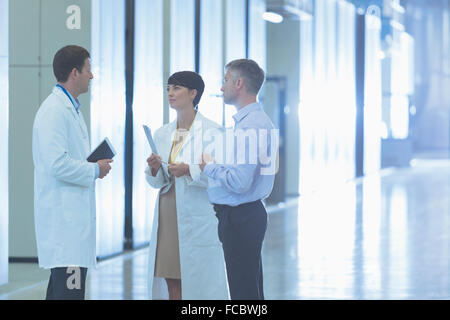 Scientists and businessman talking in factory corridor Stock Photo