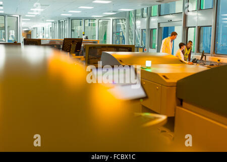 Workers at computer behind printers in printing plant Stock Photo