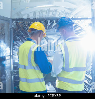 Workers with clipboard checking machinery in printing plant Stock Photo