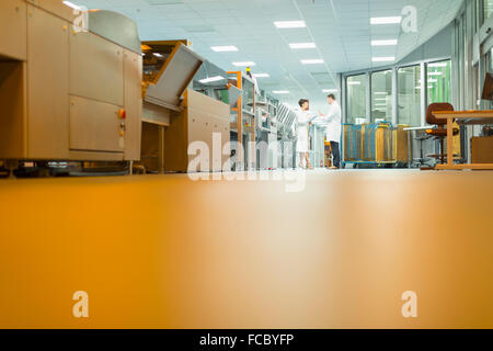 Workers talking near machinery in printing plant Stock Photo