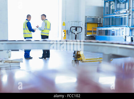 Workers in reflective clothing talking at warehouse loading dock doorway Stock Photo