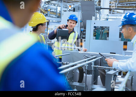 Workers talking at machinery in factory Stock Photo