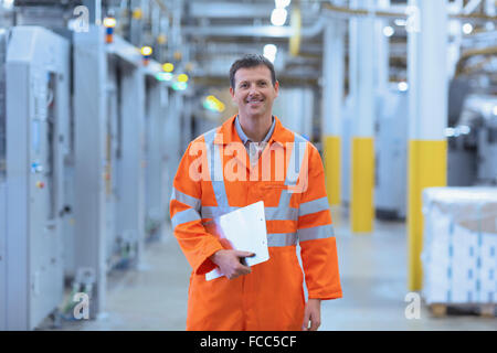 Portrait confident worker in reflective clothing with clipboard in factory Stock Photo