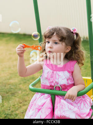 cute little girl swinging on seesaw and playing with soap bubbles Stock Photo