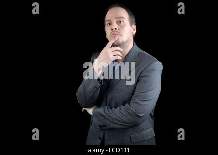young man dark gray suite thinking holding chin Stock Photo