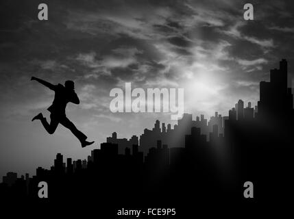 Silhouette of businessman jumping against sunset background Stock Photo