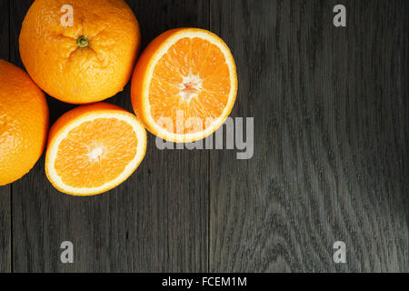three ripe oranges on wooden table one half cut shot from above Stock Photo