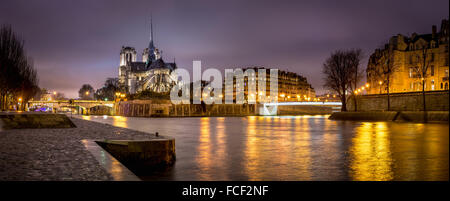 Evening panoramic of Notre Dame de Paris Cathedral on Ile de La Cite with city lights reflecting on the Seine River. France Stock Photo