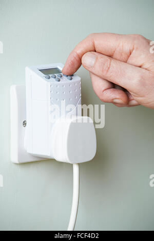 Close Up Of Hand Adjusting Timer Switch In Plug Socket Stock Photo